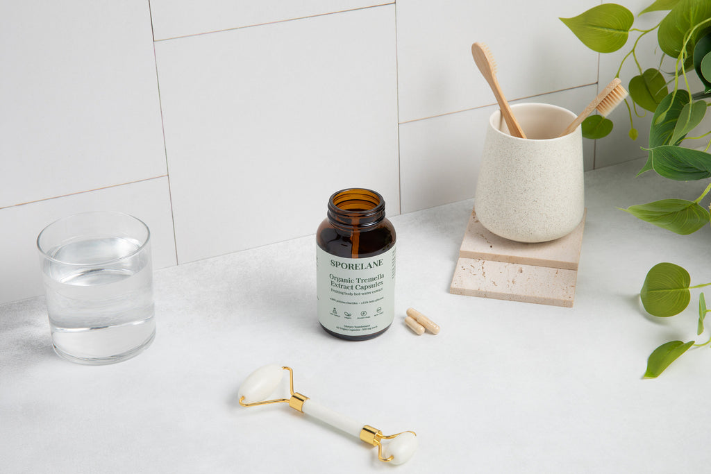 Sporelane Organic Tremella Extract Capsules with water, facial roller, bamboo toothbrushes, and green plant leaves