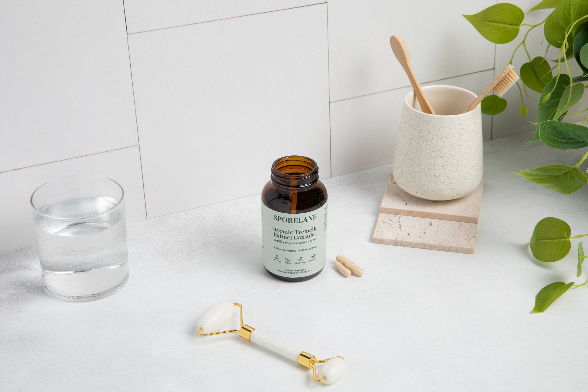 Sporelane Organic Tremella Extract Capsules with water, facial roller, bamboo toothbrushes, and green plant leaves